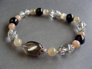 ブレスレットです。（シリコンゴム（２重・結び技法）使用・内周16.0ｃｍ）　スモーキークォーツ（ブラウン）リラックス効果・豊かな感受性　フェルドスパー【ムーンストーン】（オレンジ）女性らしさ・感受性・喜び　クォーツ（クリア）健康・能力・明晰・完璧・宇宙的意識・感受性・沈着冷静・豊かな感受性　ハイパーシーン（ブラック・シラー効果）欲しいものが手に入る・周囲の信頼を得る